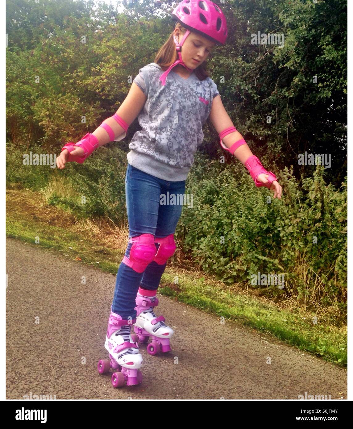 Young girl learning to roller skate in a park Stock Photo Alamy