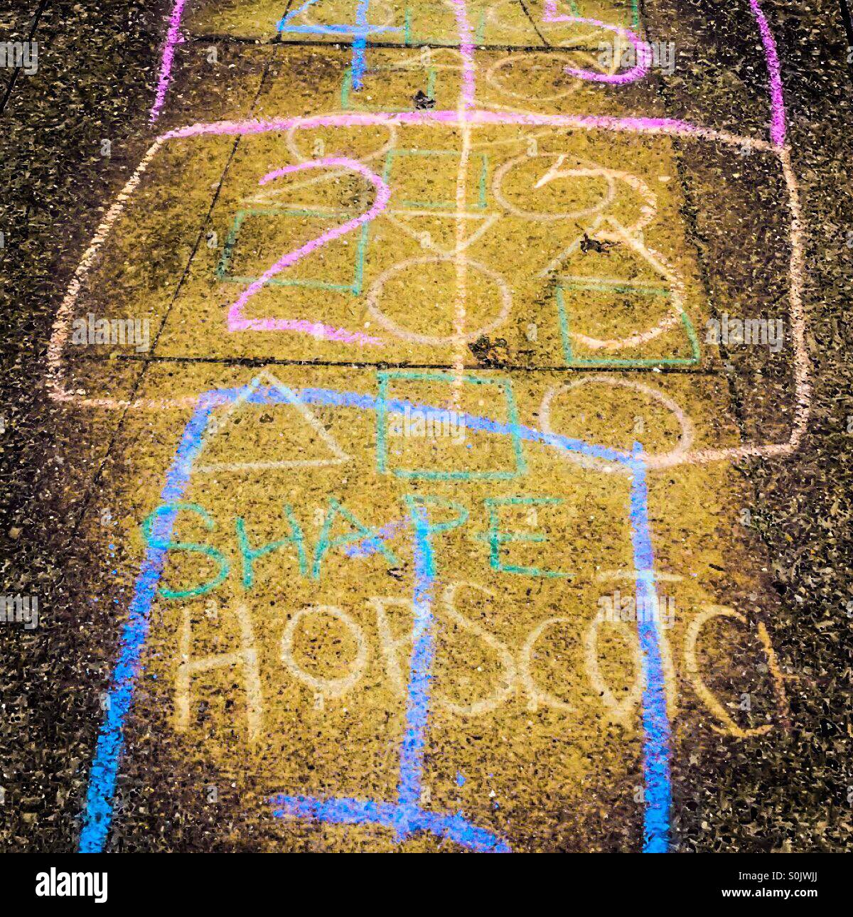 Shapes and numbers jumbled in hopscotch. Like a double exposure. Overlay in many colours on the pavement. Ontario, Canada. In chalk. Until rain washes it away. - Smartphone Captured Stock Image