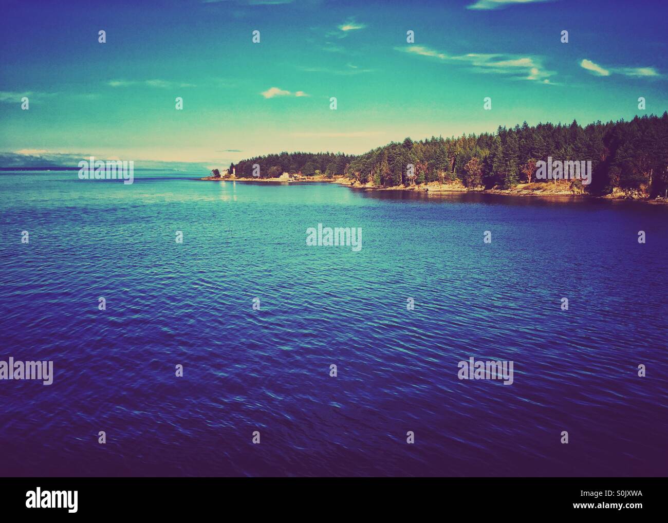 An island with small lighthouse in the Salish Sea in British Columbia. - Smartphone Captured Stock Image