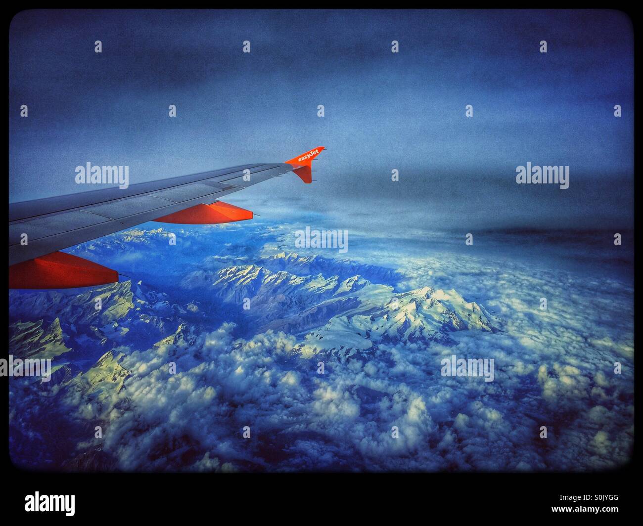 View of a Boeing Aircraft Wing and Engines and The Alps Mountains from Row 21 of an Easyjet flight, flying over Italy. Photo Credit - COLIN HOSKINS. - Smartphone Captured Stock Image