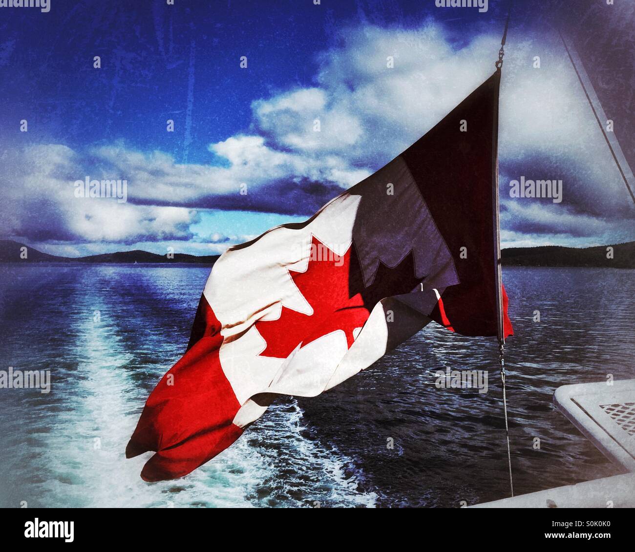 Canadian flag flying in the wind at the back of large boat. - Smartphone Captured Stock Image