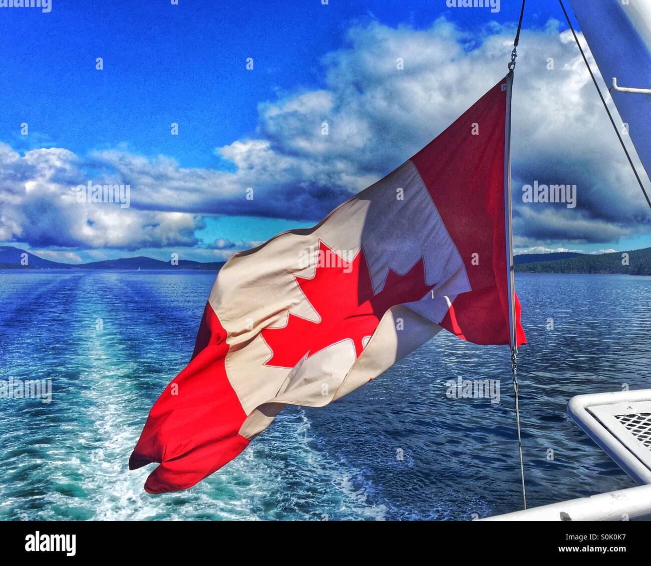 Canadian flag flying in the wind at the back of a large boat. - Smartphone Captured Stock Image