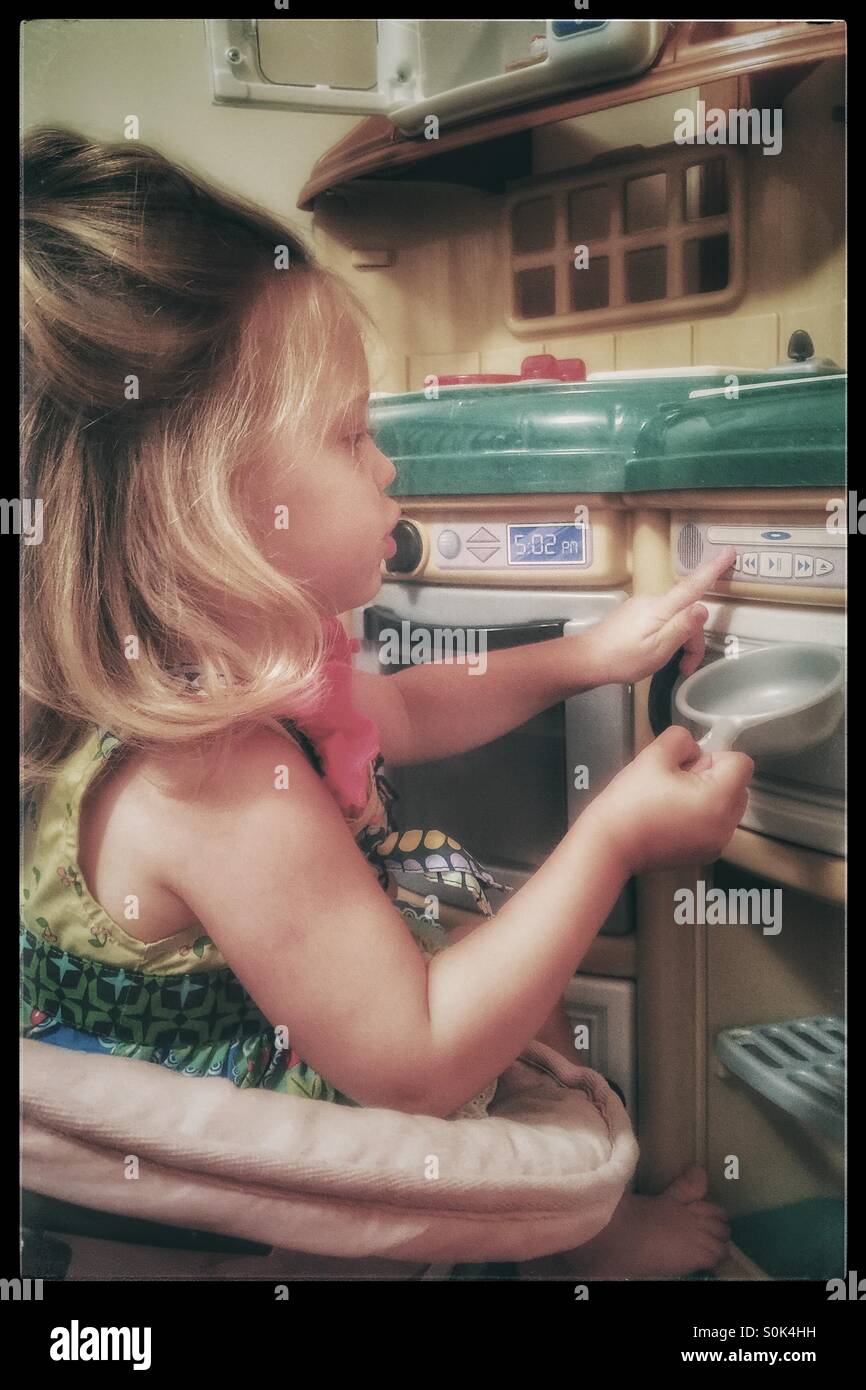 Little girl pretending to cook in her kitchen Stock Photo