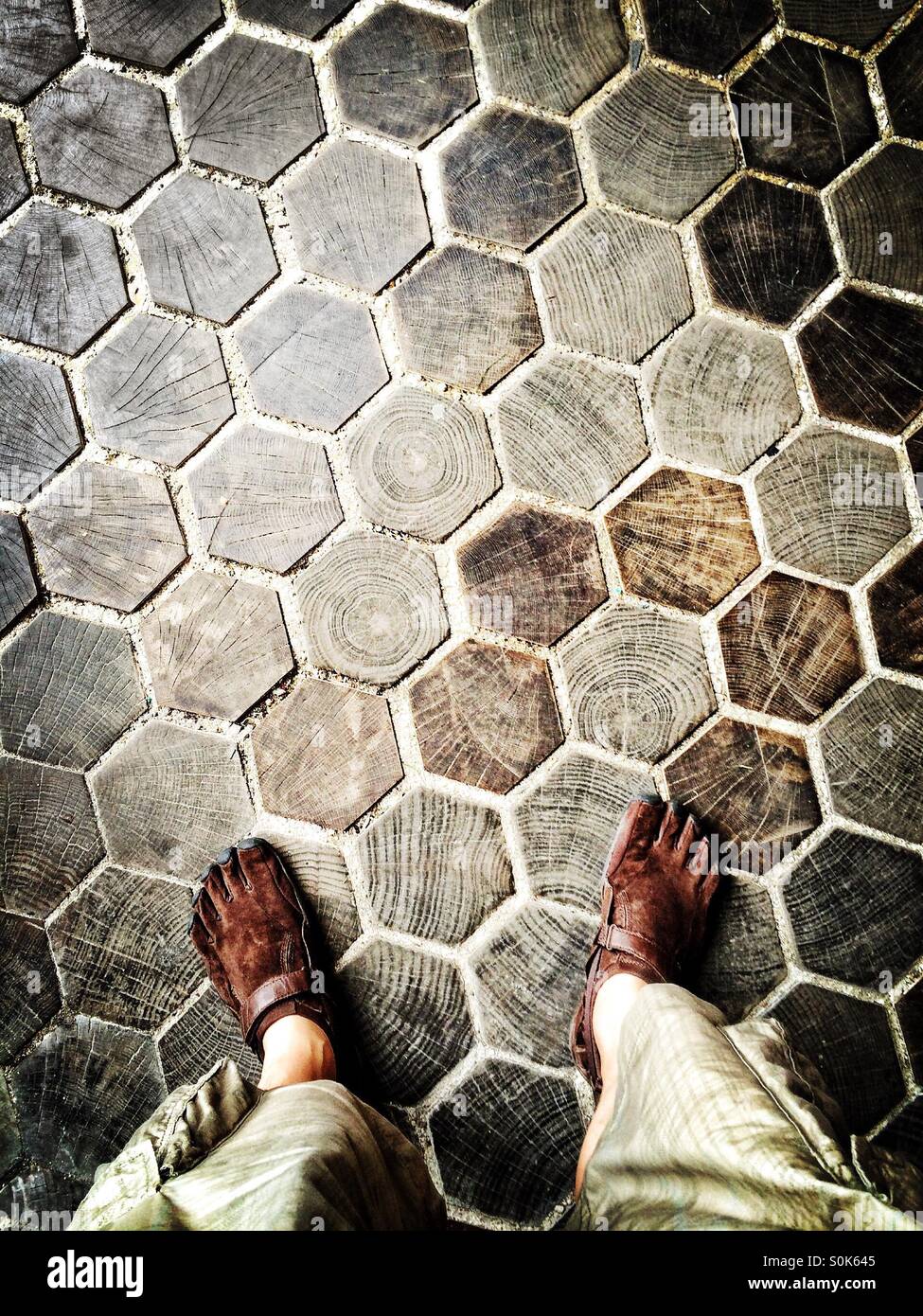 Man wearing Vibram Fivefingers shoes standing on hexagonal wooden block flooring at the entrance hall of Trinity College Dublin, Ireland - Smartphone Captured Stock Image