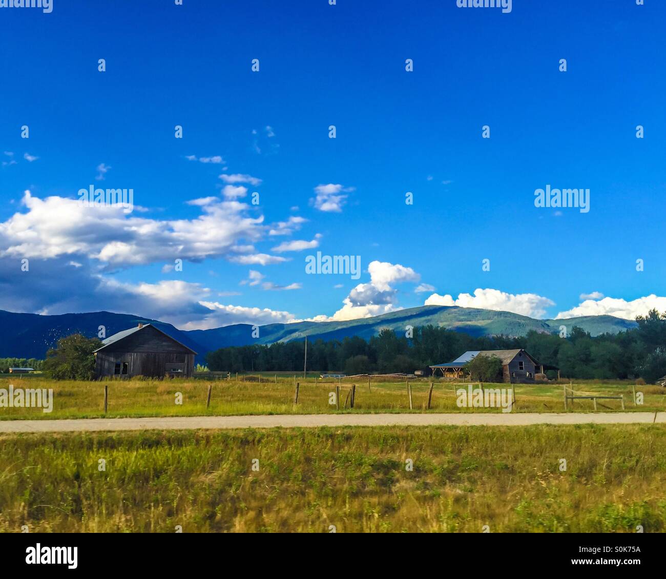 Old barns on fields and mountains in the background on a sunny late summer day. - Smartphone Captured Stock Image