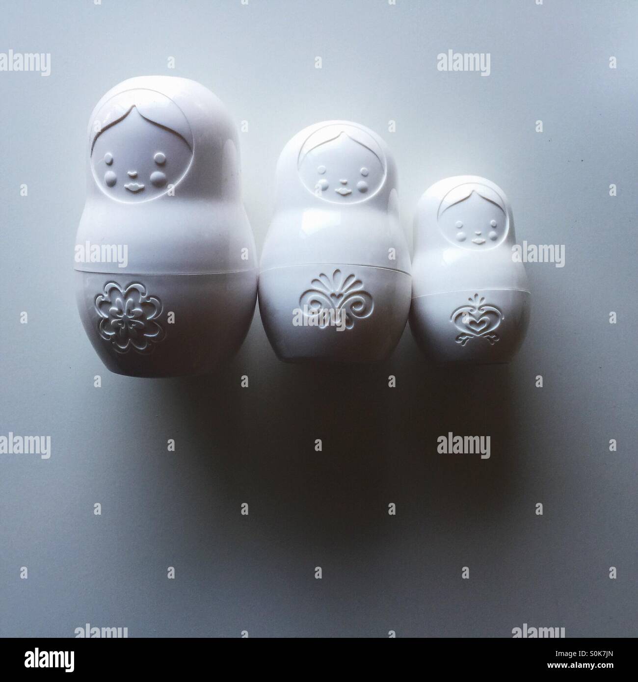 Three white matryoshka nesting dolls on white table - Smartphone Captured Stock Image