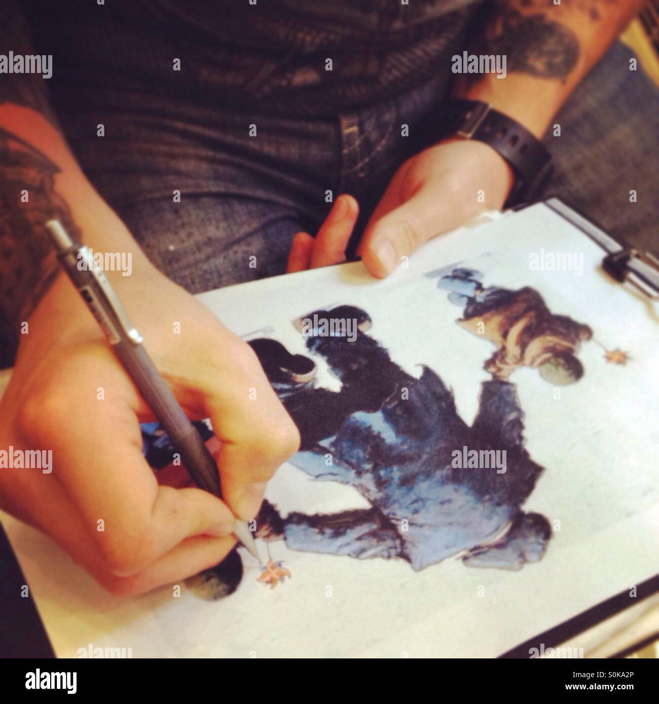 Tattoo artist tracing contours of picture - Smartphone Captured Stock Image