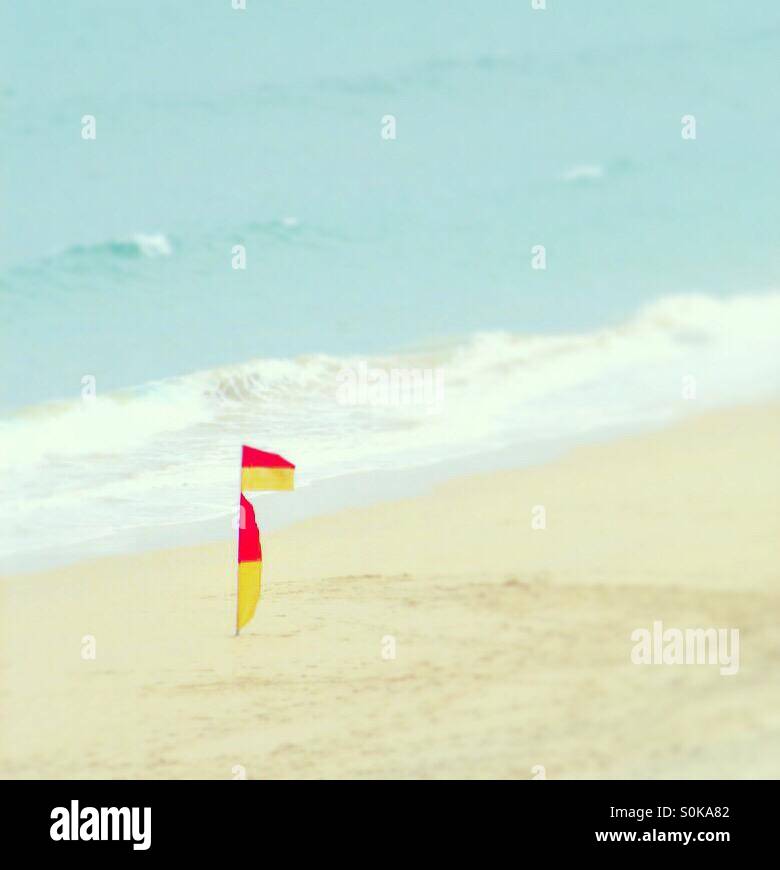 A lifeguard warning flag standing alone on an empty beach - Smartphone Captured Stock Image