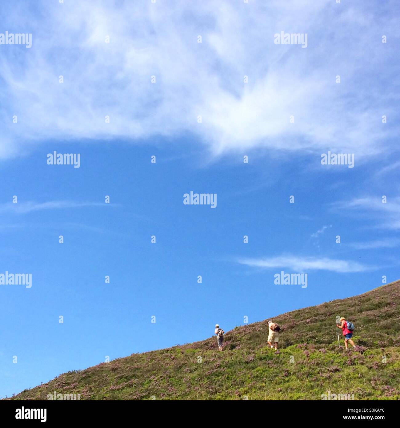 People hiking under a blue sky in the Pyrenees in France Stock Photo