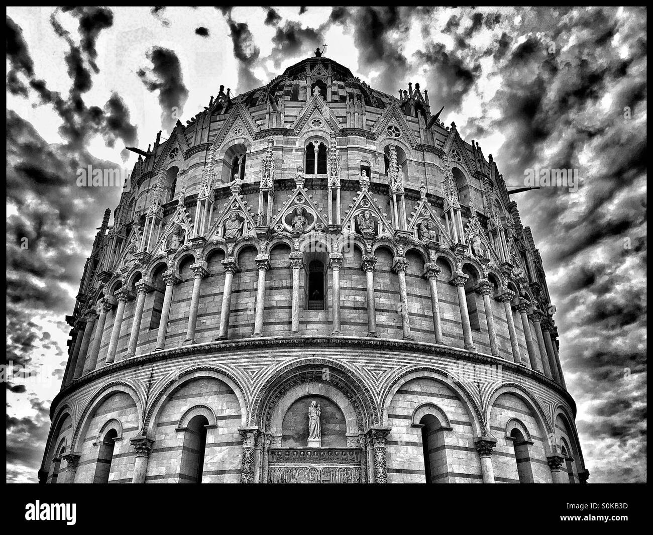 A Monochrome Image of the Baptistery in The Field of Miracles, Pisa, Tuscany, Italy. A moody sky behind signals the potential of a thunderstorm. Photo Credit - COLIN HOSKINS. - Smartphone Captured Stock Image