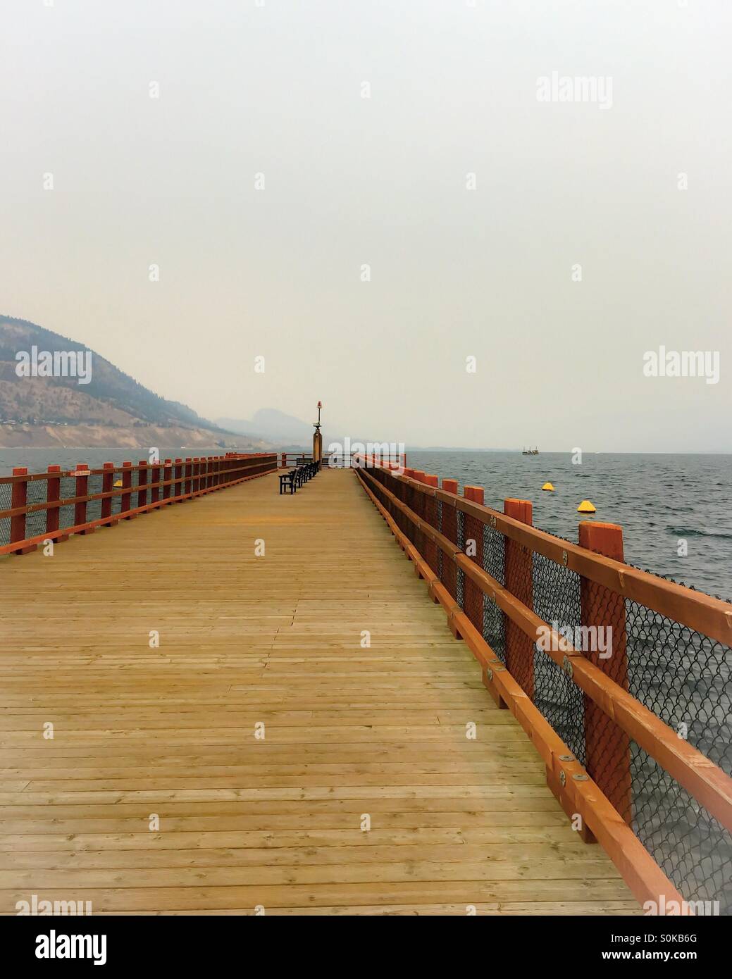 A pier sits empty on the lake on a grey summer day. - Smartphone Captured Stock Image