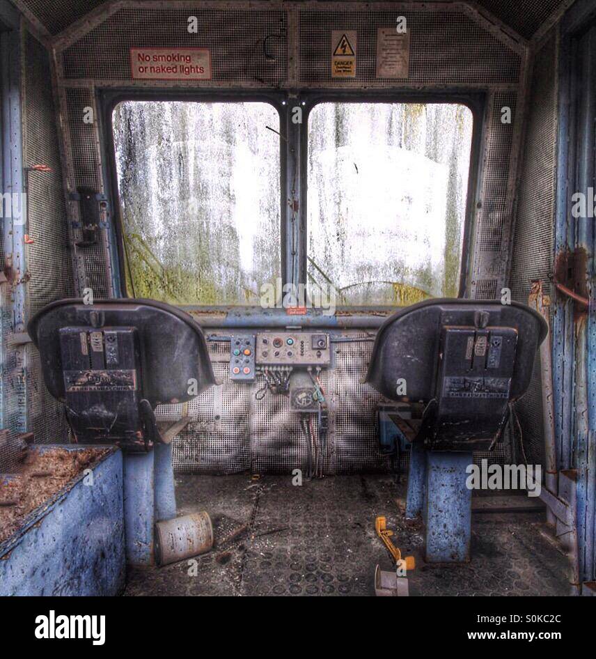 The inside of a derelict locomotive cab with driving controls, seats and in a state of disrepair. - Smartphone Captured Stock Image
