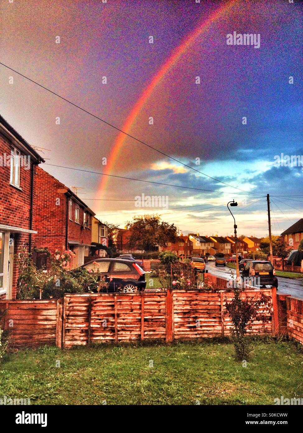 Up above the streets and houses, rainbow climbing high... - Smartphone Captured Stock Image