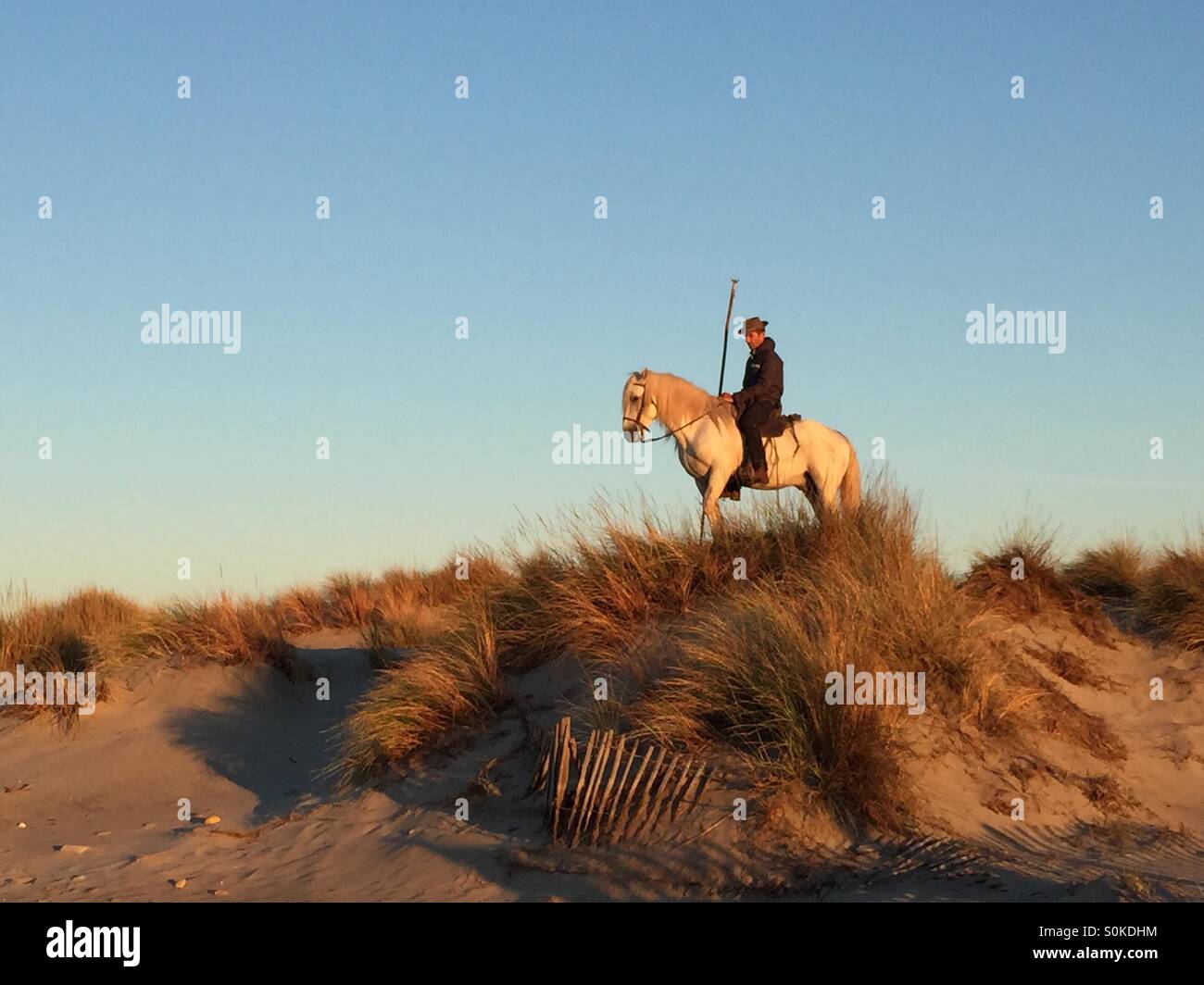 Camargue rider holding a stick on the top of a sand dune Stock Photo