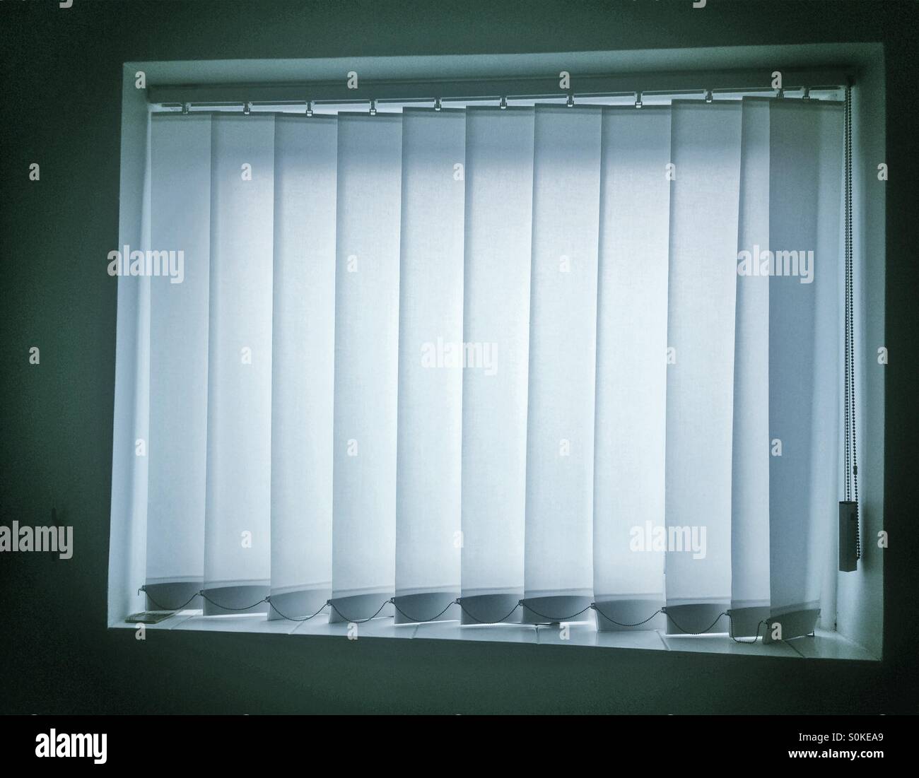 Vertical white blinds drawn against light. - Smartphone Captured Stock Image