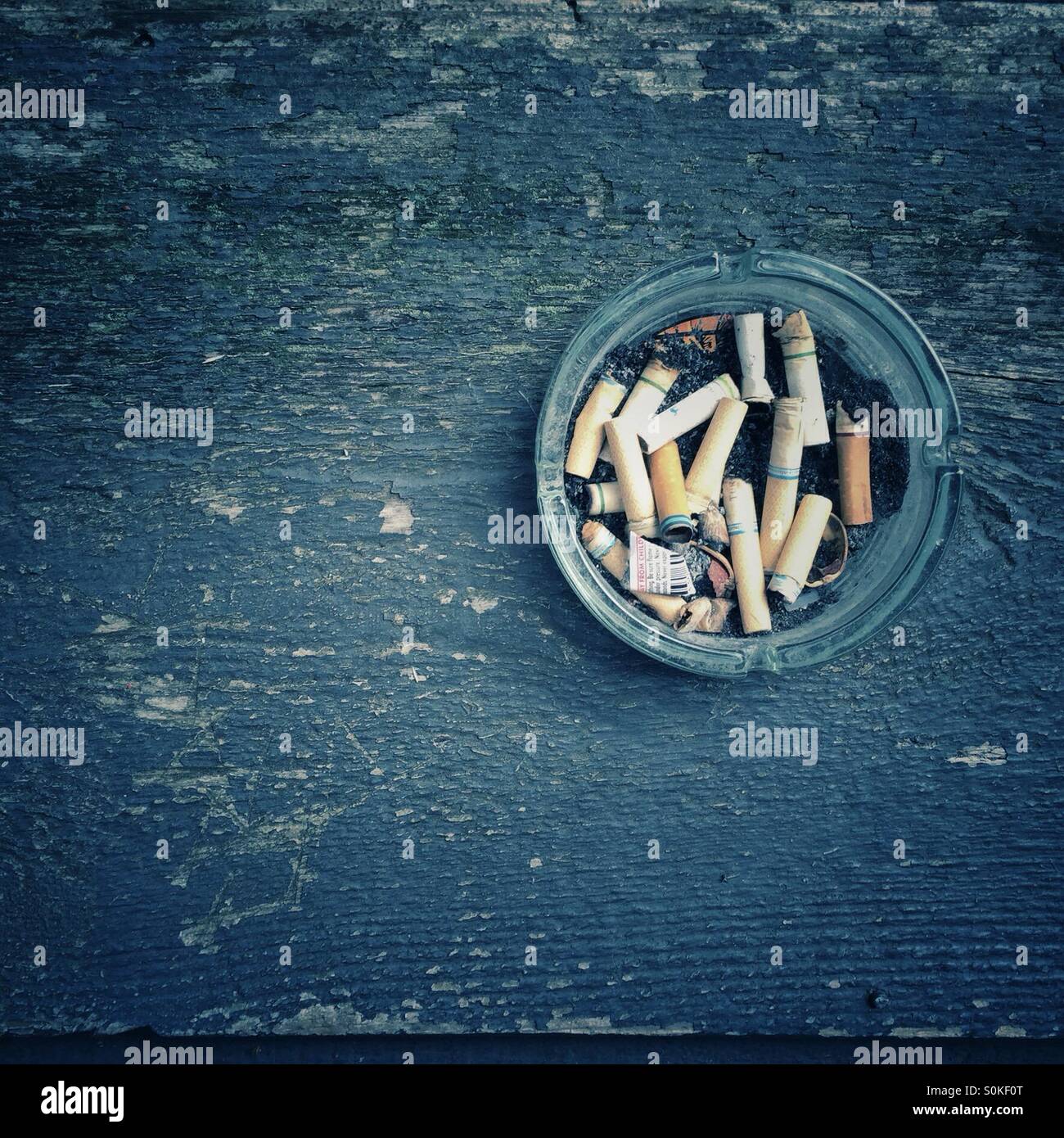 A jar full of cigarette butts on a old porch railing Stock Photo