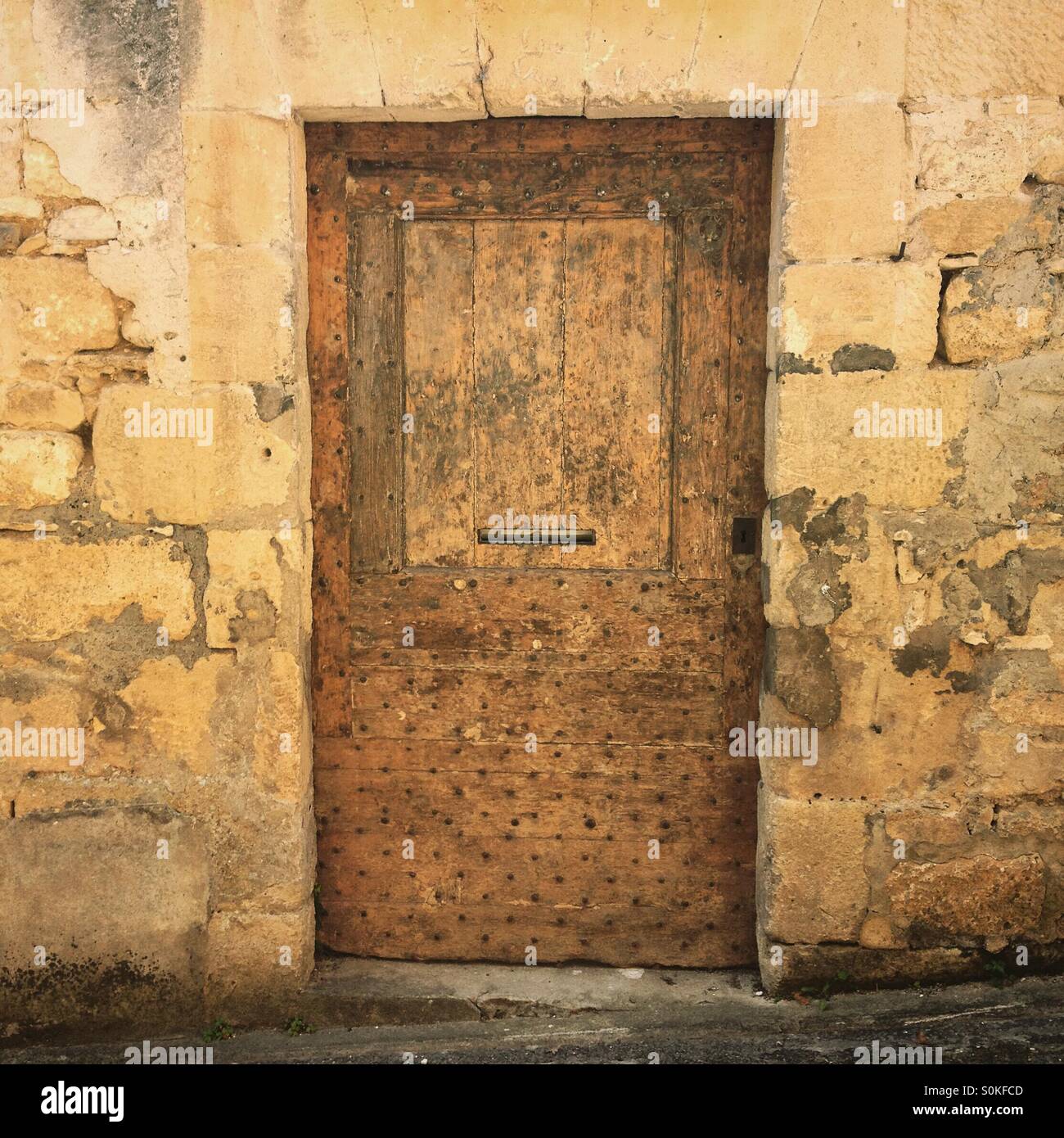 An ancient studded wooden doorway on the side of a house in St Cyprien, Dordogne, France. Security concept. Mobile phone photo with some phone or tablet post processing. - Smartphone Captured Stock Image