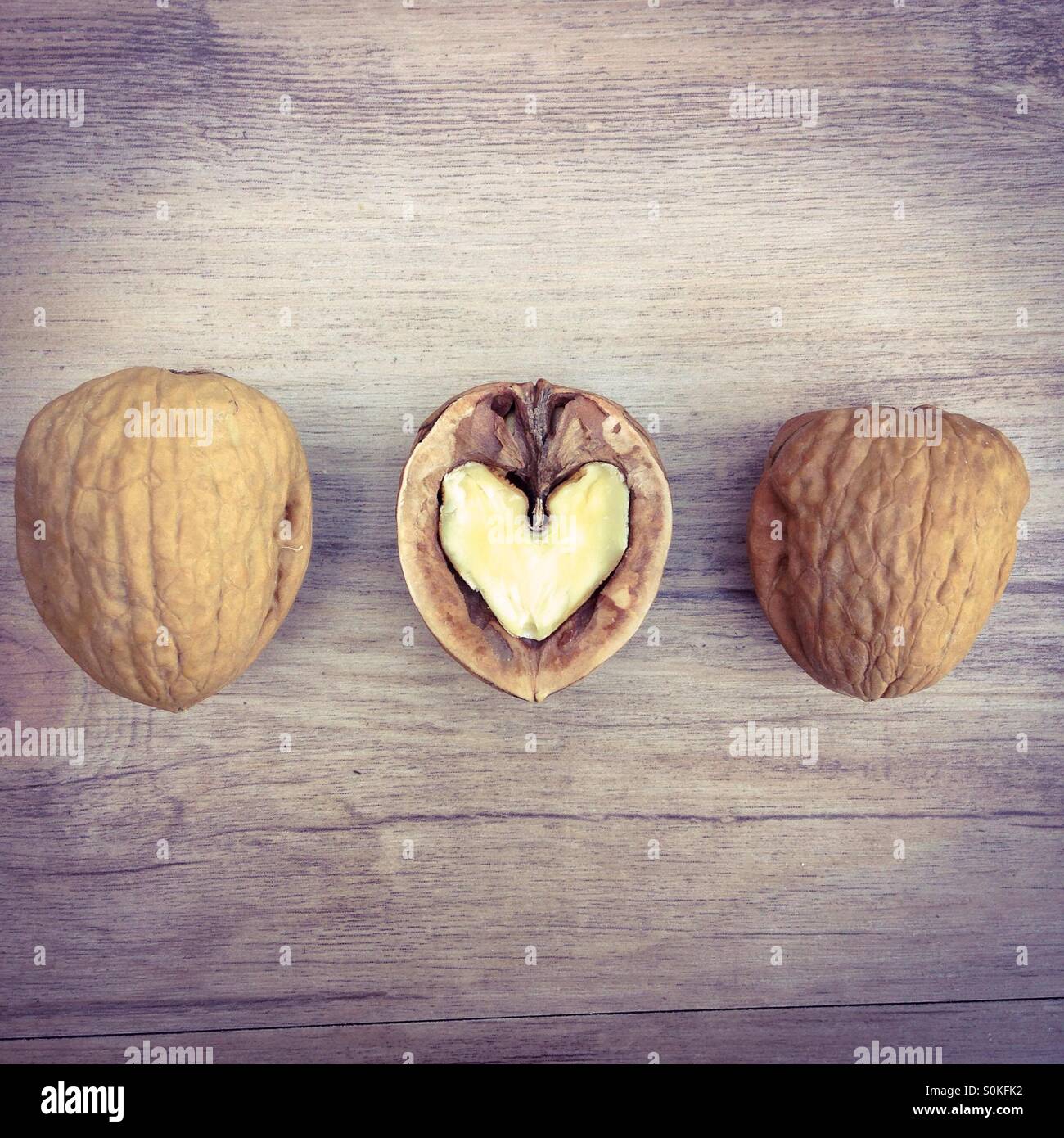 Three nuts in a row. The one in the middle is open and has a heart shaped interior. Nuts are healthy and very good for your heart. Stock Photo