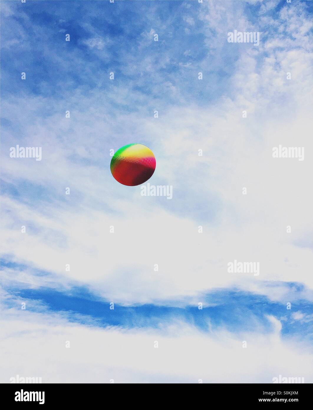 A rainbow colored rubber ball against a blue sky. - Smartphone Captured Stock Image A rainbow colored rubber ball against a blue sky. - Smartphone Captured Stock Image