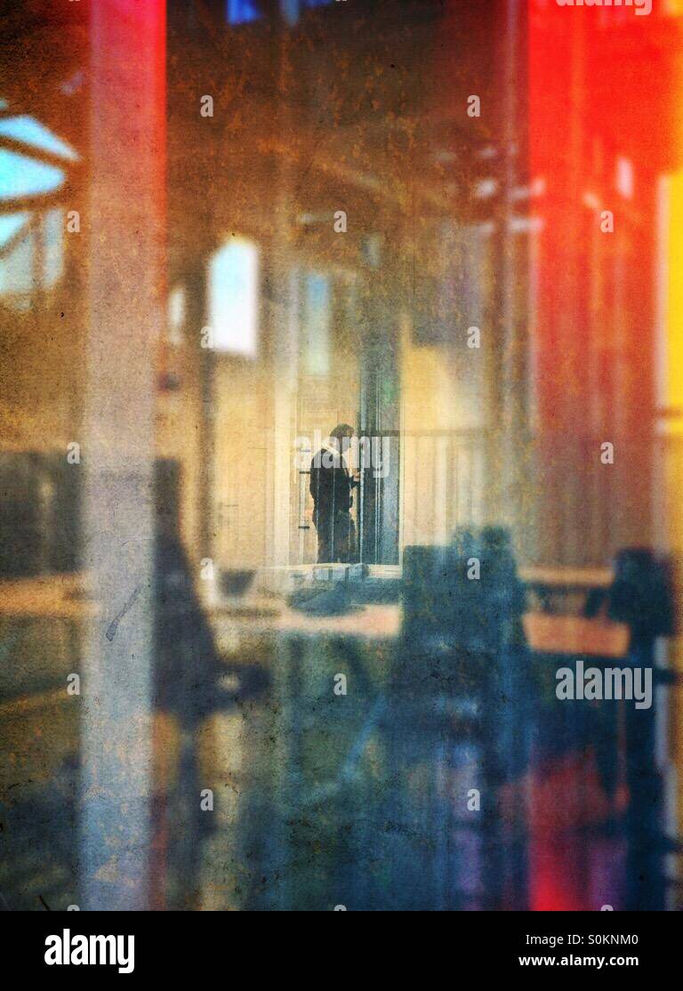 Lone man seen through an office window, standing at the entrance of a meeting room. - Smartphone Captured Stock Image