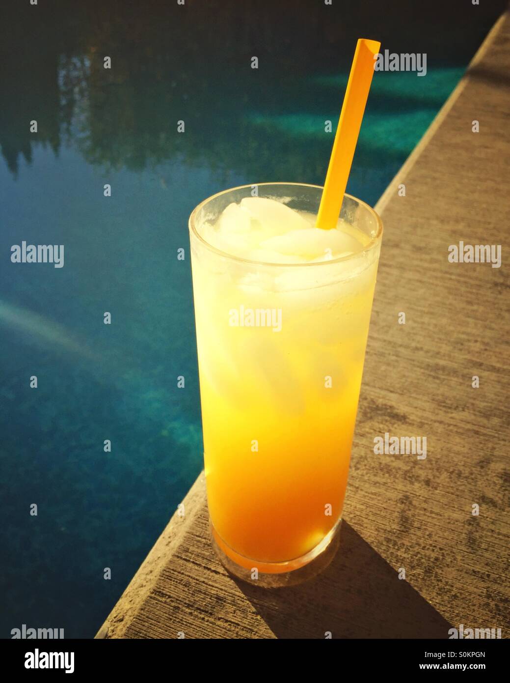 Warm afternoon refreshment poolside. A glass of icy tropical drink sits next to the blue waters of a swimming pool. - Smartphone Captured Stock Image