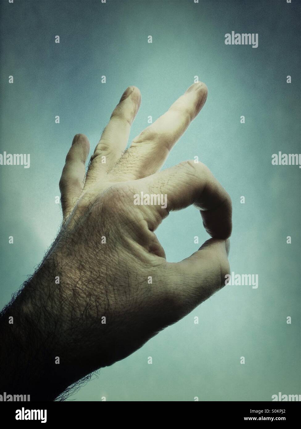 Hand giving OK sign against blue sky - Smartphone Captured Stock Image