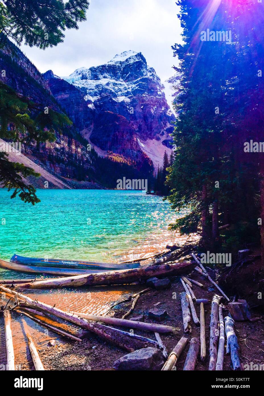 A peekaboo view from the forest of lake Moraine with mountains in the backdrop. - Smartphone Captured Stock Image