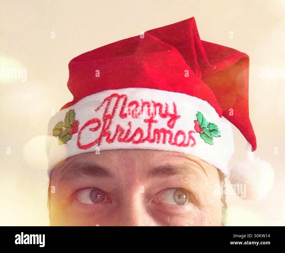 Partial portrait of a man looking left way, with a Christmas hat. Text: Merry Christmas - Smartphone Captured Stock Image
