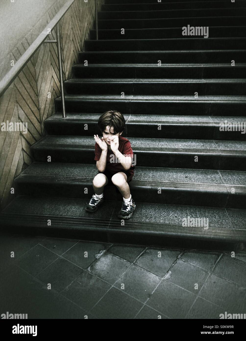 Five years old boy sad sitting on the stairs - Smartphone Captured Stock Image