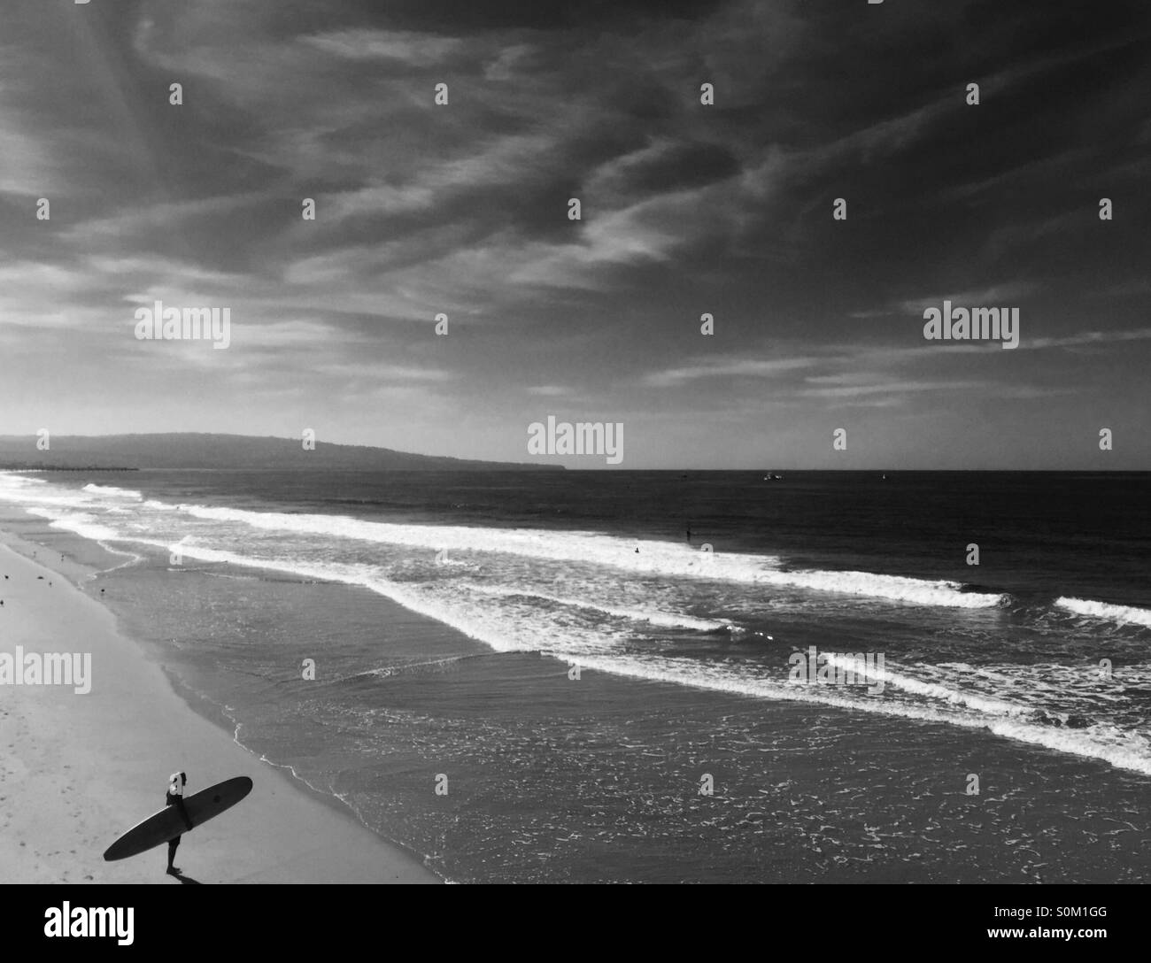 Surfer stands on the beach looking at the surf. Manhattan Beach l, California USA. Stock Photo