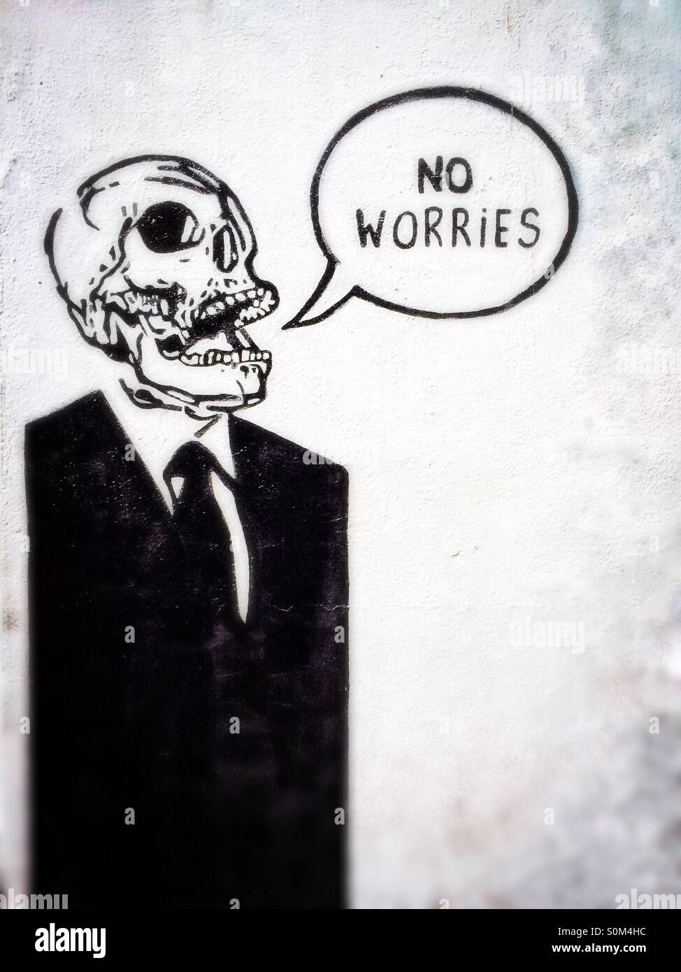 Street art of a human skeleton in suit with speech bubble containing the words No Worries, wall in Dublin, Ireland Stock Photo
