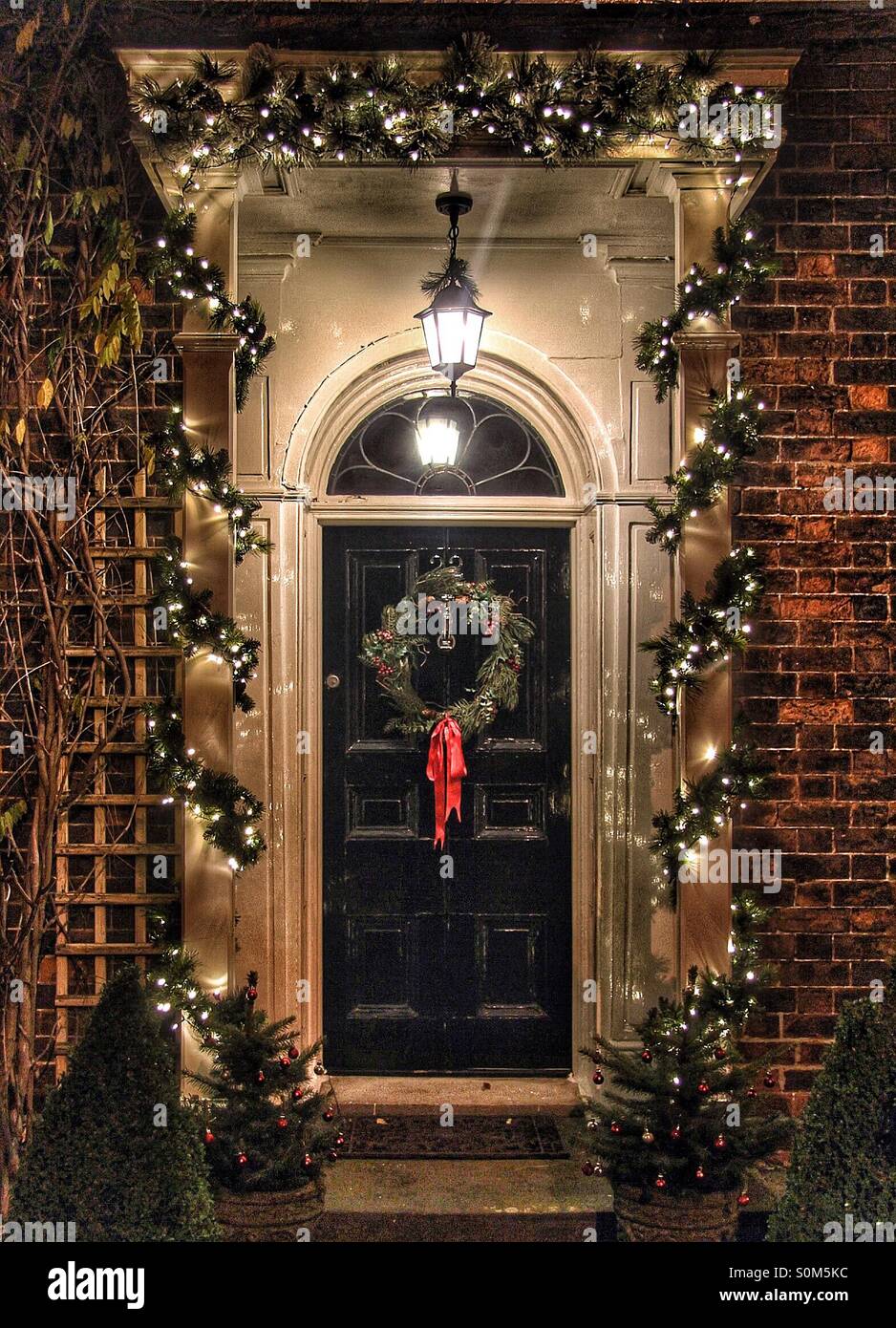 A traditional doorway decorated for Christmas with a wreath and lights. Stock Photo