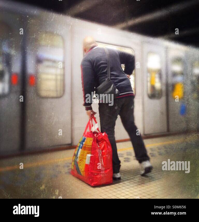 Man with big red bag preparing to embark on an arriving subway train - Smartphone Captured Stock Image
