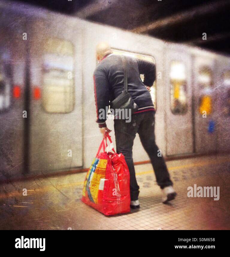 Man with big red bag preparing to embark on an arriving subway train - Smartphone Captured Stock Image