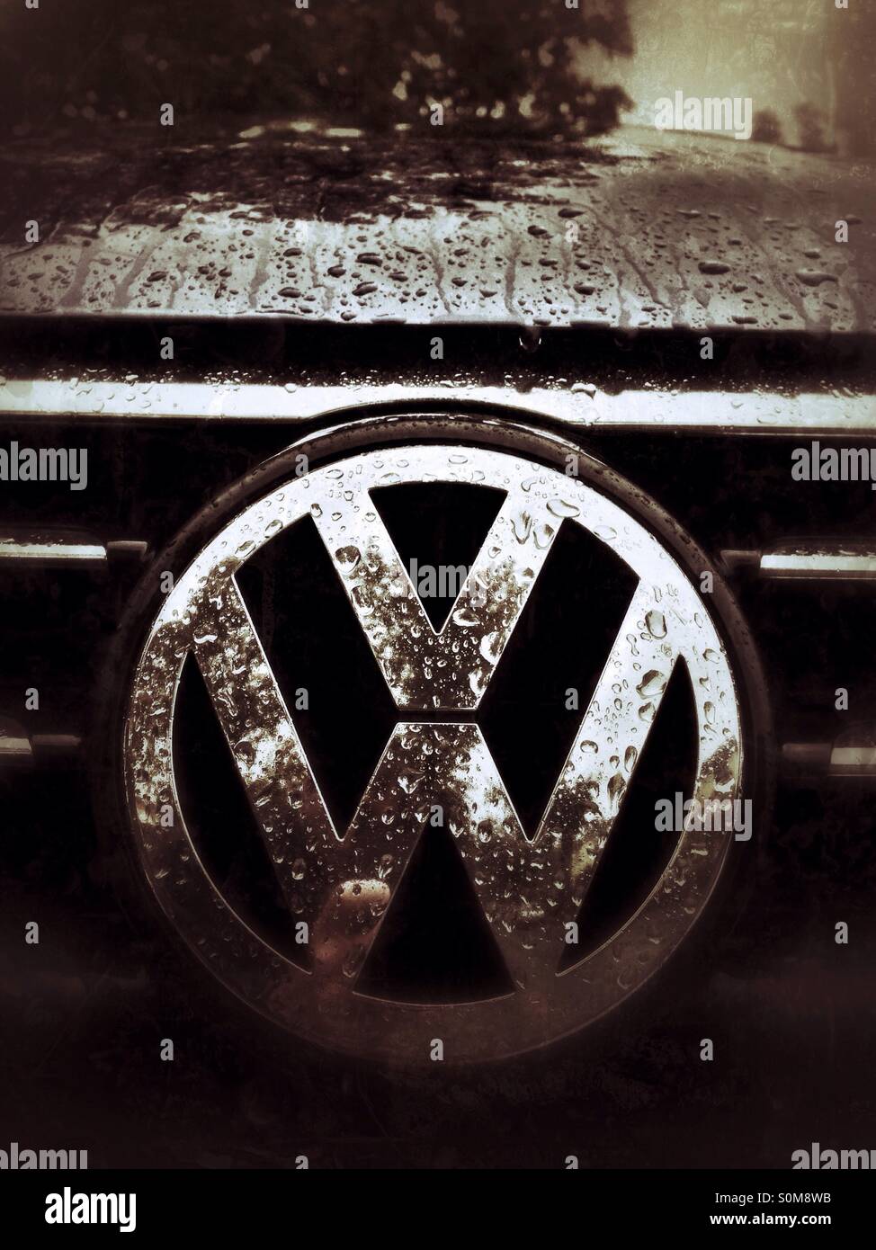 VW logo on the front of the car wet with rain Stock Photo