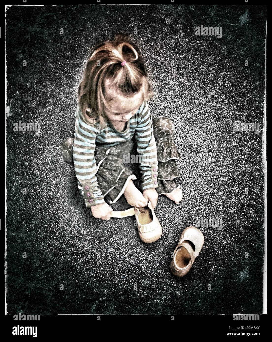 Little girl putting her shoe on the wrong foot Stock Photo Alamy