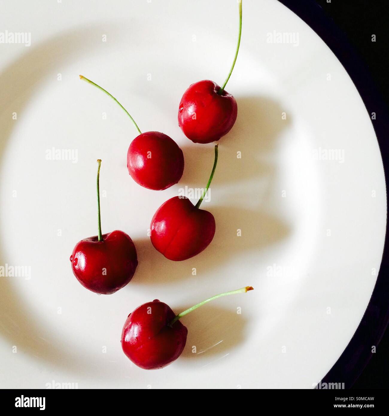 Five cherries on a white plate Stock Photo - Alamy