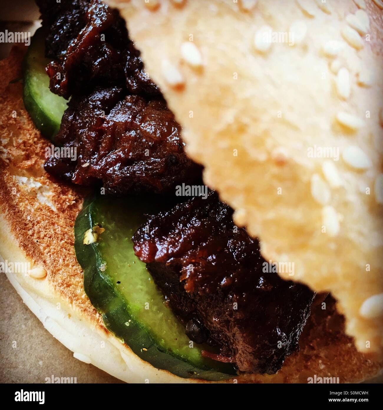 Brisket burnt ends burger with pickled cucumber. - Smartphone Captured Stock Image