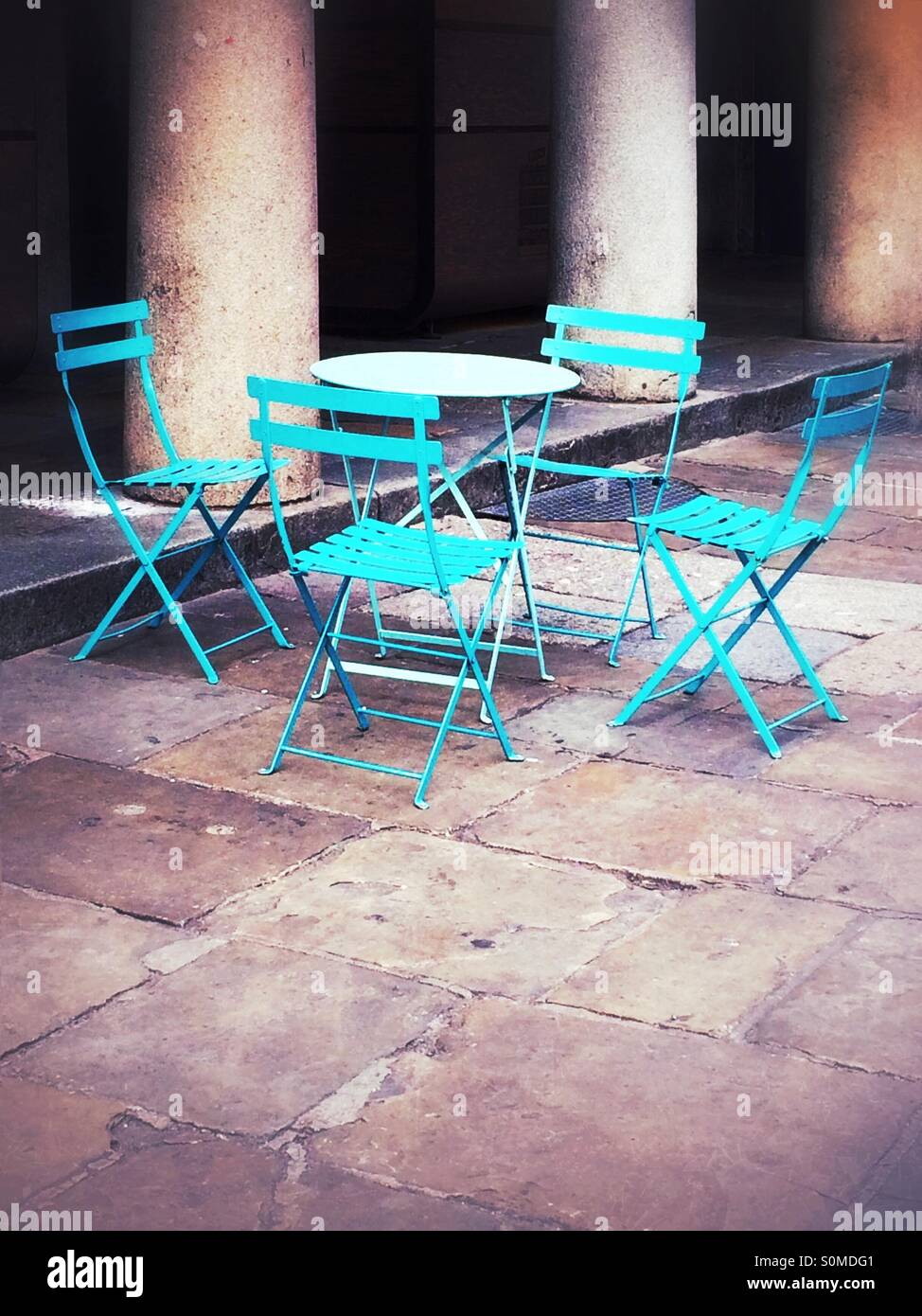 Cafe table and four chairs by stone pillars. - Smartphone Captured Stock Image
