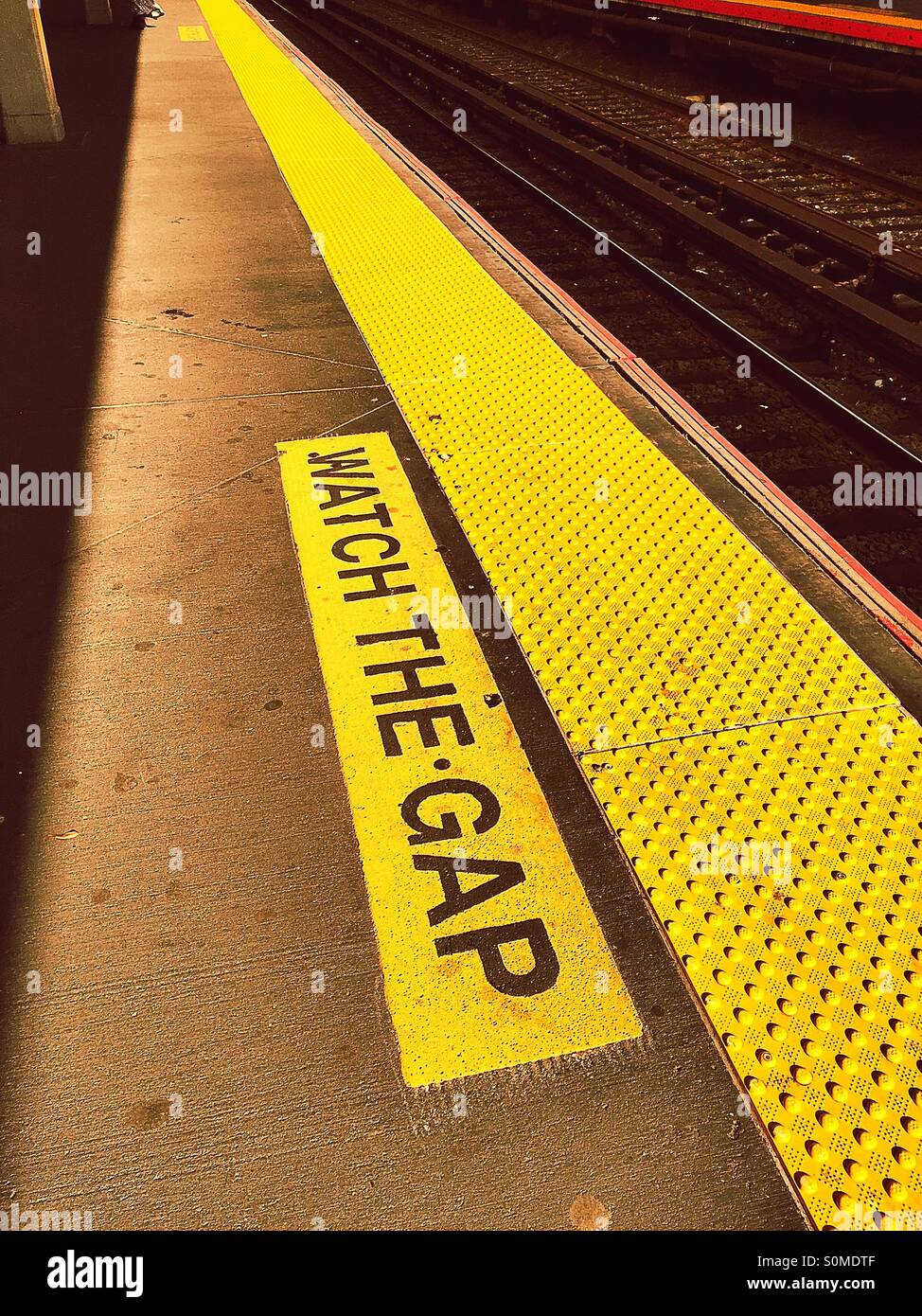 Watch the gap warning sign on NYC subway platform. Stock Photo