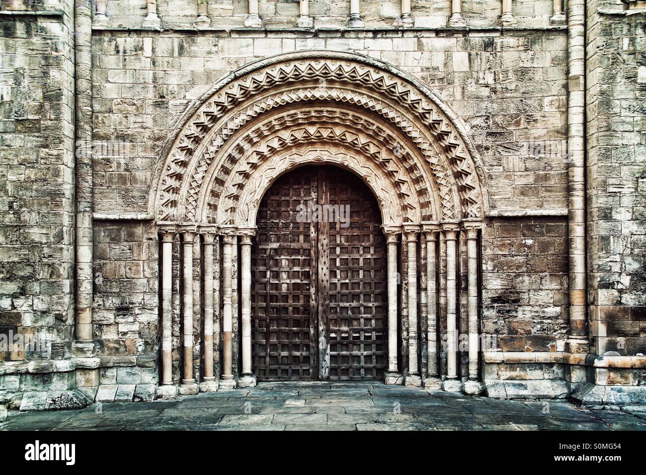 A heavy wooden church doorway with ornate stone carvings and pillars. - Smartphone Captured Stock Image