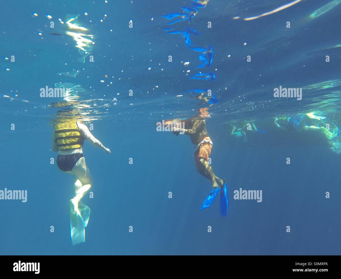 Two people in the sea shot from underwater wearing flippers Stock Photo