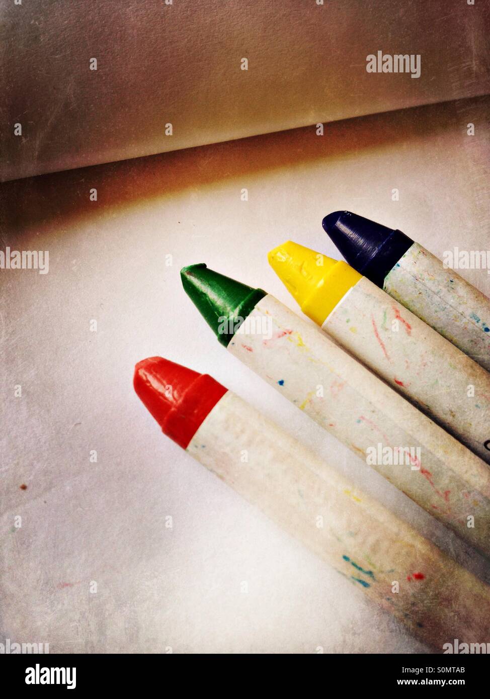Four colourful crayons on a notepad Stock Photo