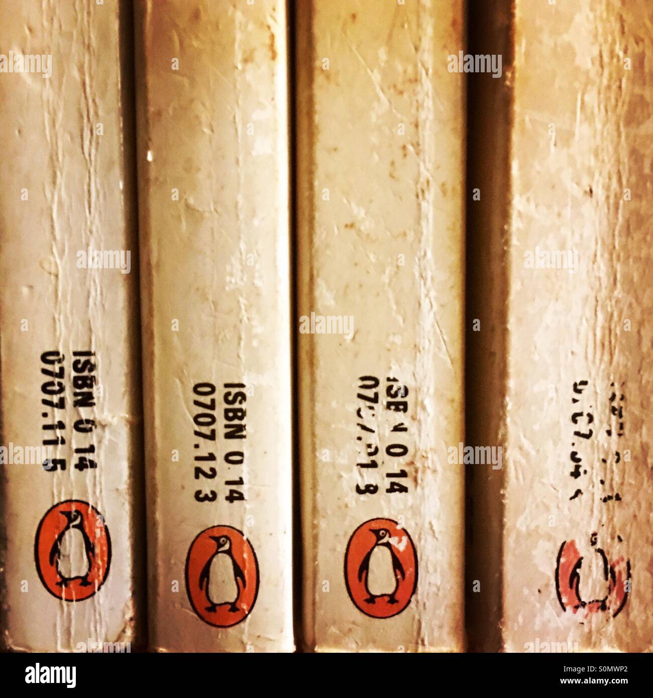 Four used Penguin books stacked on a book shelf. - Smartphone Captured Stock Image