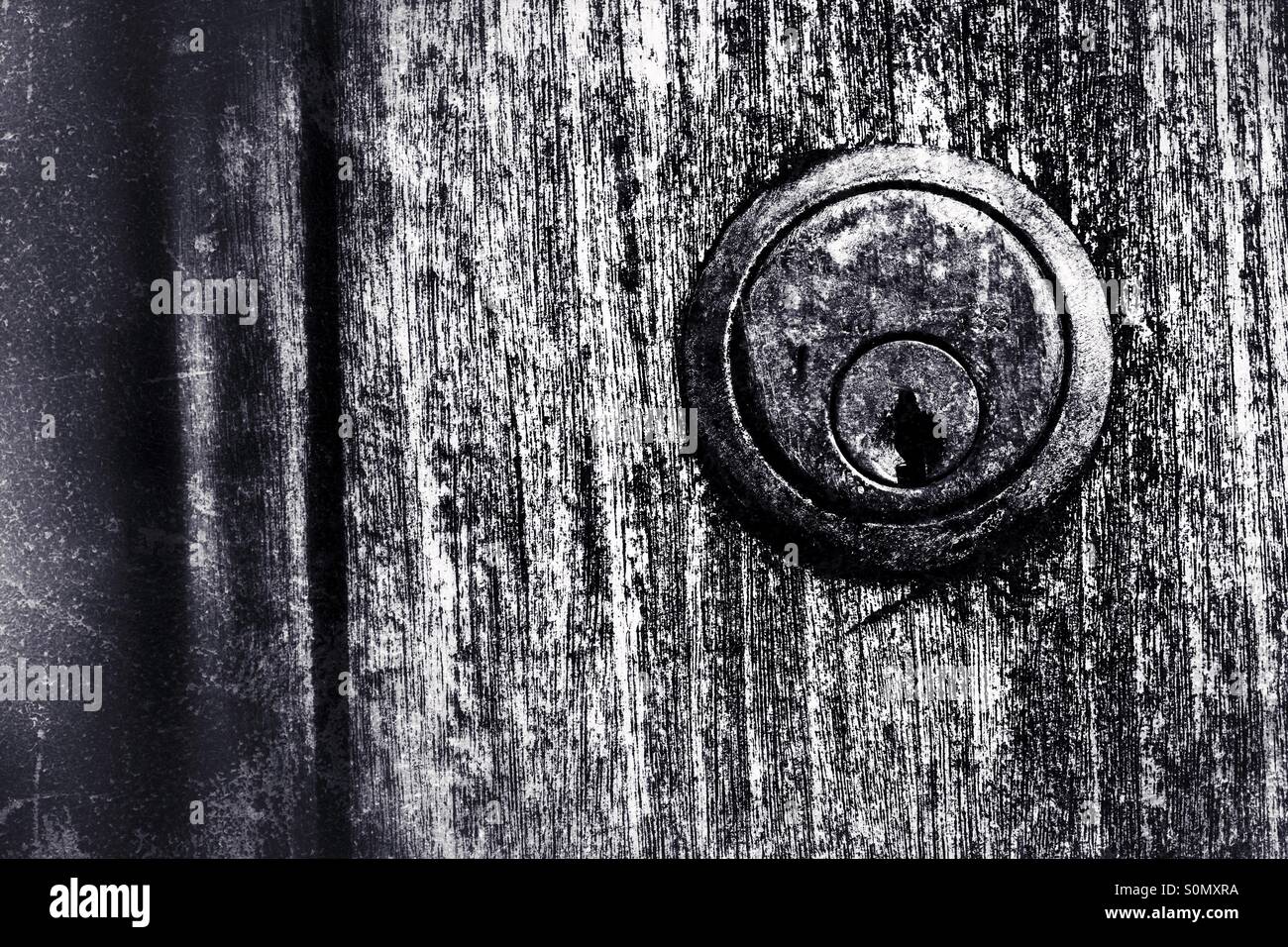 A worn and rusty Union door lock on a a grainy, split wooden door. Black and white image. Stock Photo