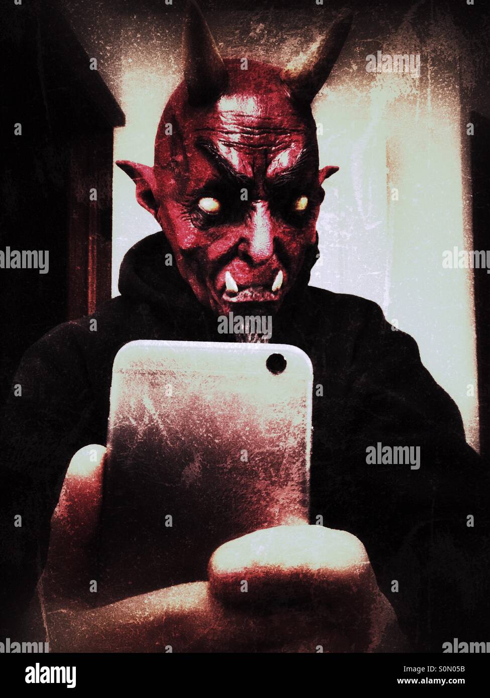 Man in a devil mask takes a selfie Stock Photo