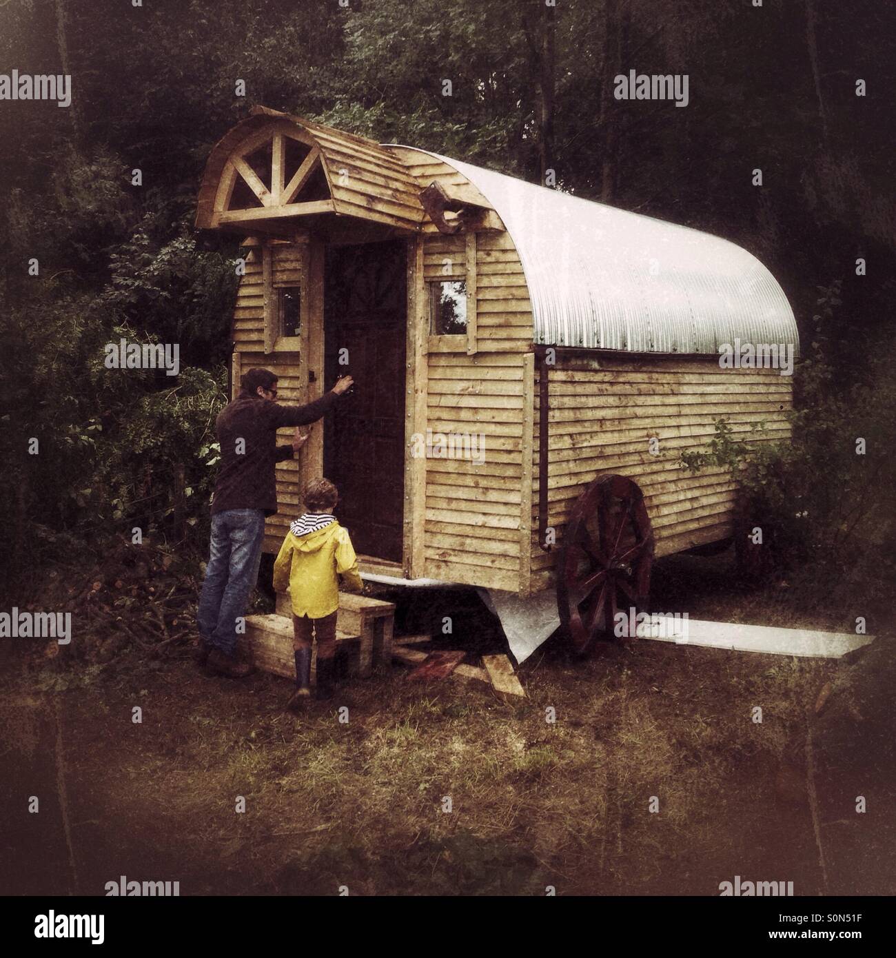 Father and son entering a wooden shepherds hut, Hampshire, England. - Smartphone Captured Stock Image