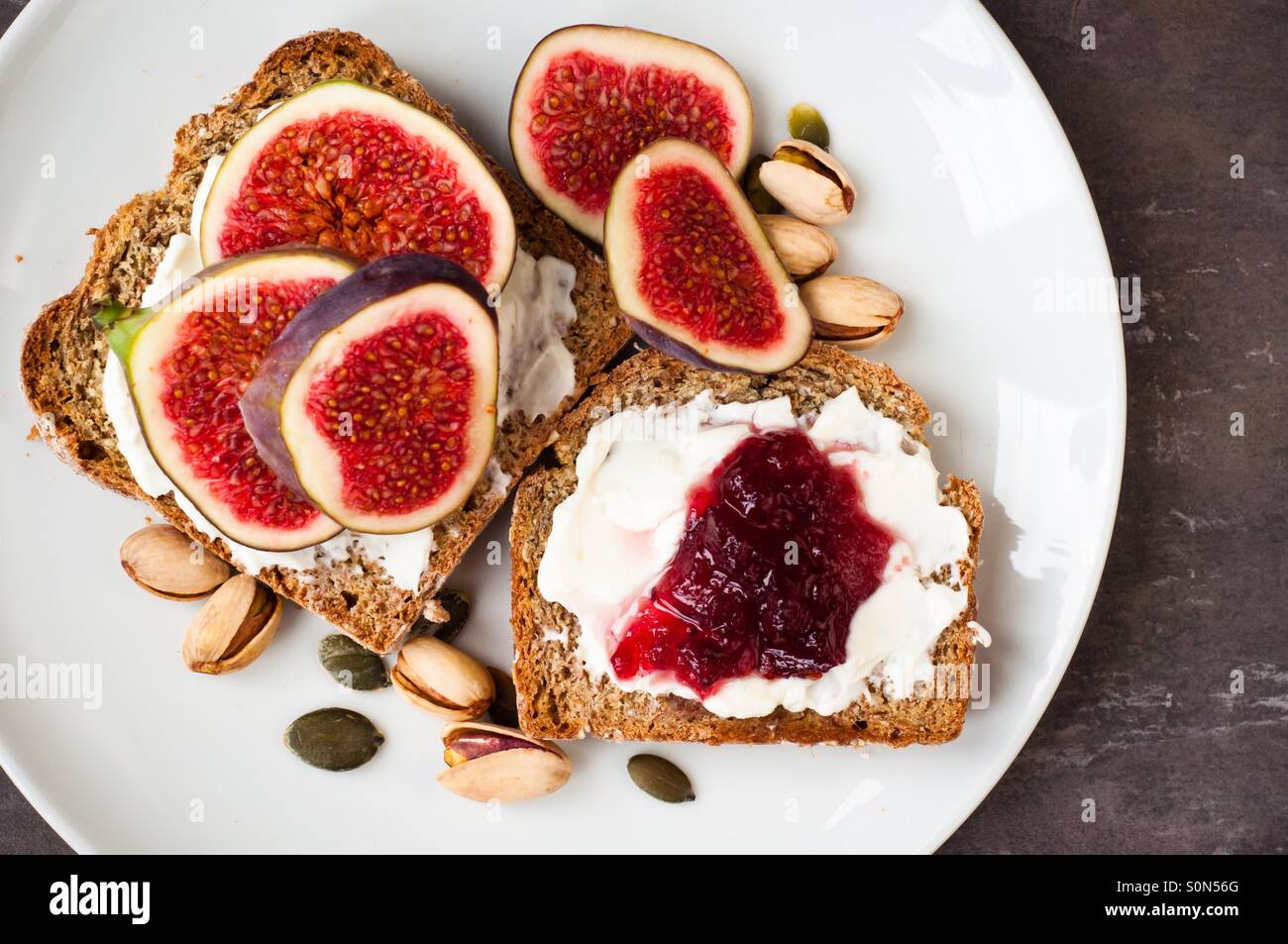 Healthy fruit topped open sandwich of Wholemeal rye bread with strawberry, blackberry, grilled peach and fig. Served on a wooden board. Stock Photo