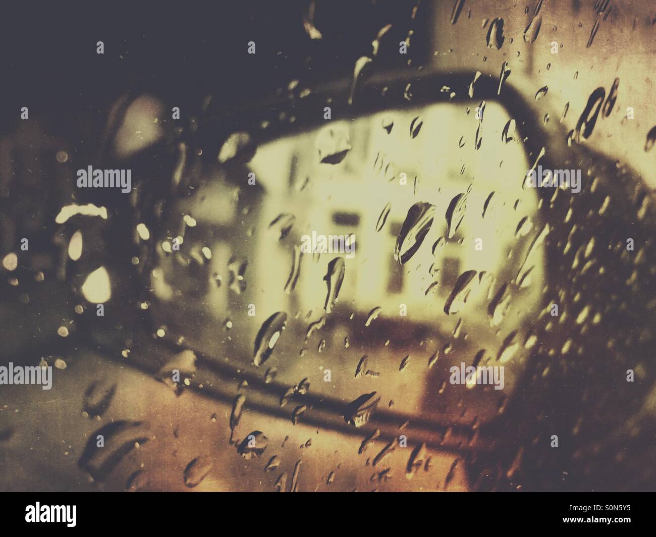 Rearview mirror of a car seen through raindrops on the side window. - Smartphone Captured Stock Image