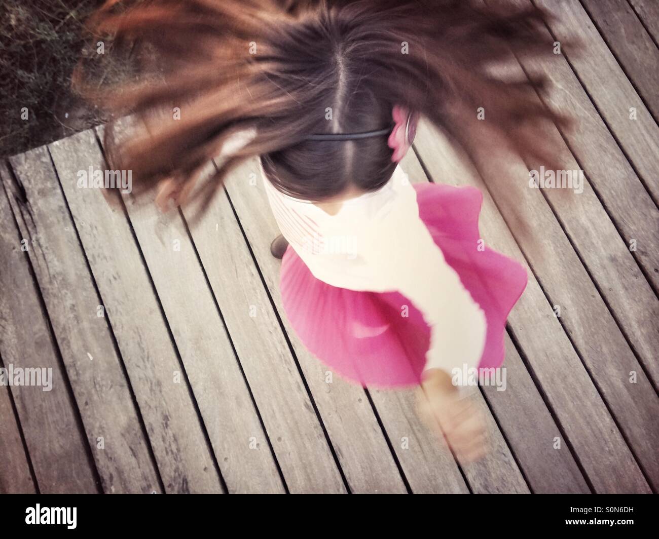 Girl in pink skirt turning on wood walk Stock Photo